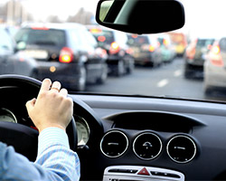 Blick über die Schulter eines Autofahrers durch die Frontscheibe in einen Verkehrsstau.