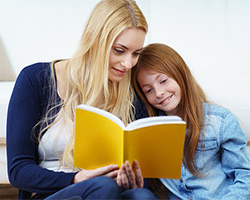 Eine junge Frau schaut mit einem Kind ein Buch an.