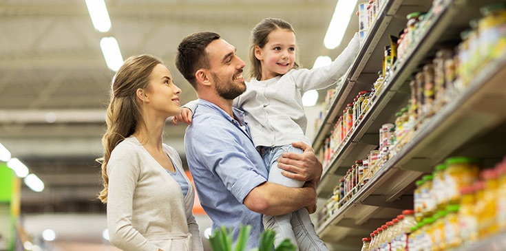 Familie mit Mutter, Vater und Kind mit Einkaufswagen im Lebensmittelgeschäft.