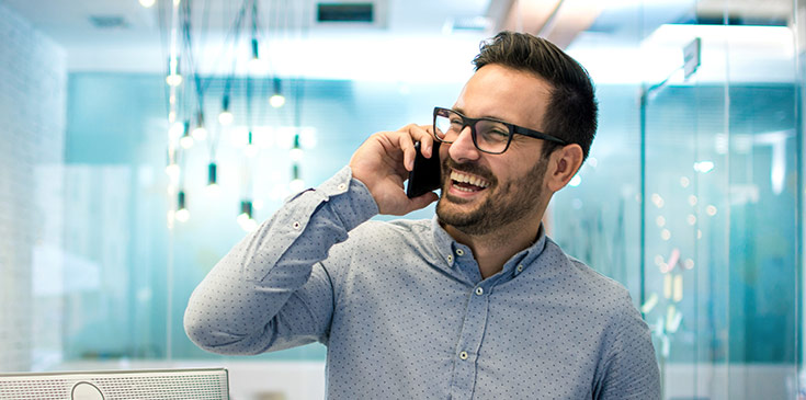 Fröhlicher Angestellter telefoniert im Büro