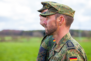 Zwei Soldaten in Tarnuniform stehen nebeneinander und blicken geradeaus.