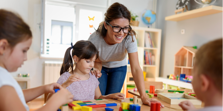 Kindergärtnerin mit Kindern, die mit buntem Holzspielzeug im Kindergarten spielen