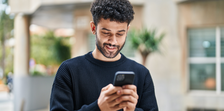 Ein junger Mann schaut auf sein Handy.