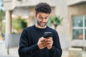 Ein junger Mann schaut auf sein Handy.