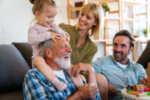 Eine Familie sitzt im Wohnzimmer zusammen und lacht.