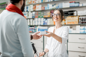 Eine Apothekerin überreicht einem Mann ein Medikament.