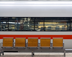 Vorbeifahrender Zug mit Bank auf Bahnhof