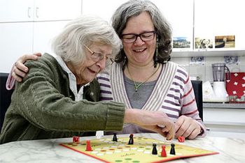 Häusliche Pflege: Eine Seniorin spielt mit ihrer Tochter ein Brettspiel.