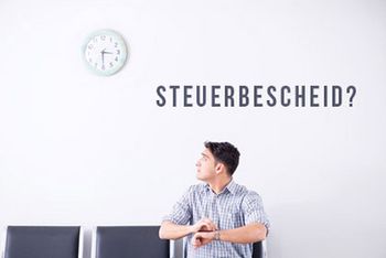 Ein Mann schaut ungeduldig auf eine Uhr an der Wand. An der Wand steht „Steuerbescheid?“